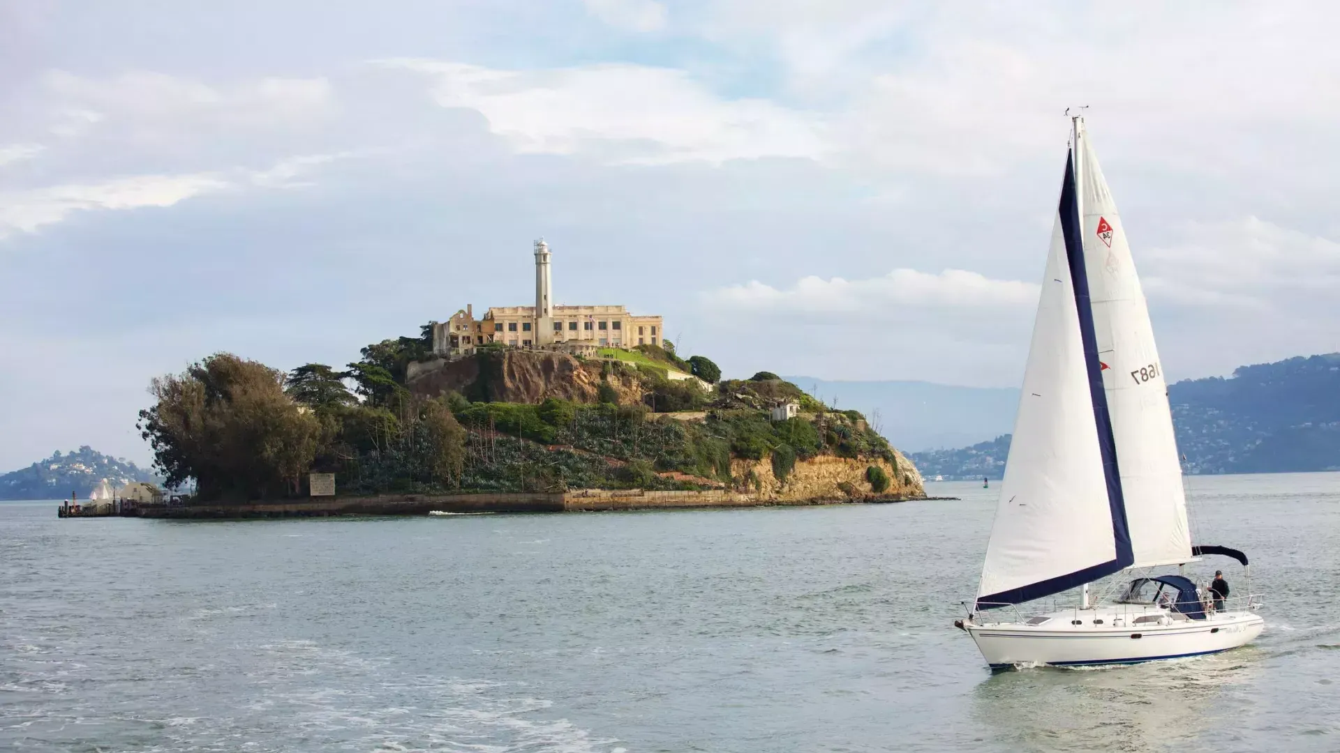 A sailboat passes in front of Alcatraz Island in San Francisco.